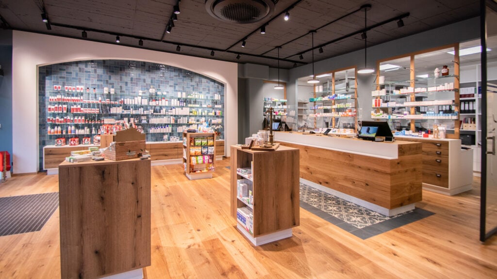 Moderne Apotheke mit Holztheke und Medikamentenregalen